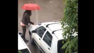 Жена се възползва от дъжда, за да измие колата си (ВИДЕО)