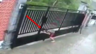 Жена се опитва да се провре през метална врата