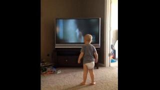 Сладко бебе имитира тренировка на мъж пред телевизора